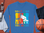 Garment Graphics offers a blue unisex DJ sweatshirt featuring a silhouette design on colorful stripes and the text Dont Stop the Music. Ideal for music enthusiasts, it is displayed with a basketball, black shorts, a towel, and a water bottle on a brown surface.