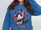 A person wears a blue Garment Graphics sweatshirt with a vibrant pony-unicorn design. The unicorn, with a multicolored mane, is adorned with stars and music notes on a pink background. Beneath the artwork, it reads I love my pony.