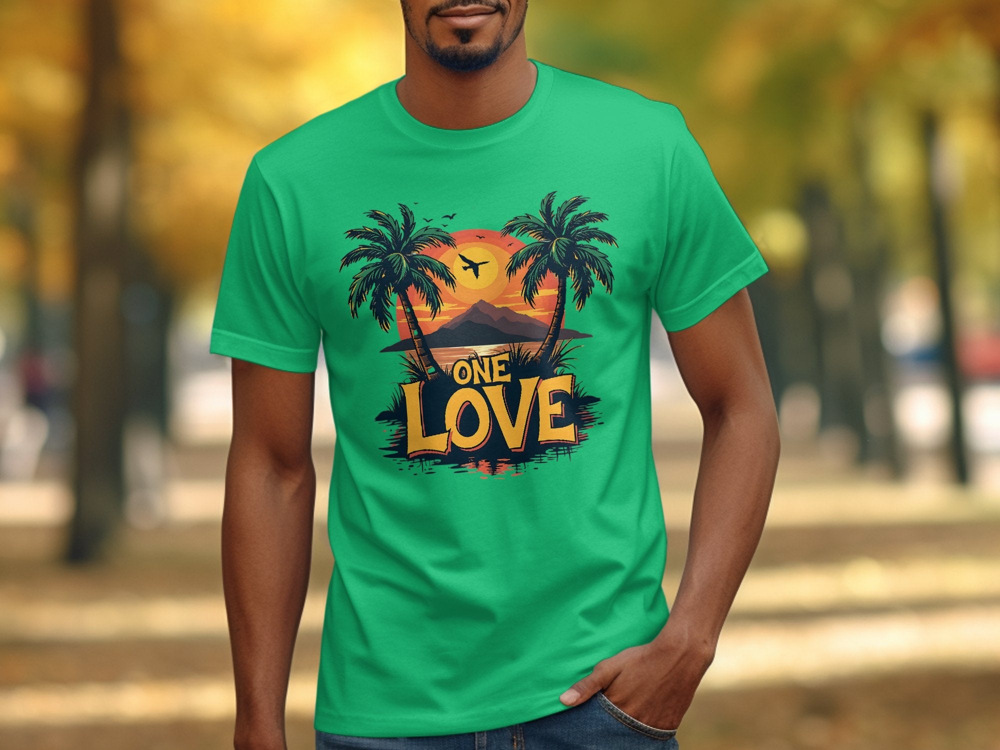 A person wearing a Garment Graphics green t-shirt with a tropical sunset, palm trees, a plane, and ONE LOVE strolls through an autumn park, captivating beach lovers.