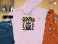 A flat lay features Garment Graphics lavender hoodie with a Classic Fit and City King Bulldog Graphic, surrounded by casual essentials: headphones, sunglasses, jeans, an orange shirt, a watch, and keys on a wooden surface.