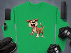 A green Garment Graphics sweatshirt with a happy brown dog illustration and floppy ears, ideal for dog lovers, is displayed on a gray surface surrounded by black sneakers, a smartwatch, a smartphone, a portable speaker, and two dumbbells.