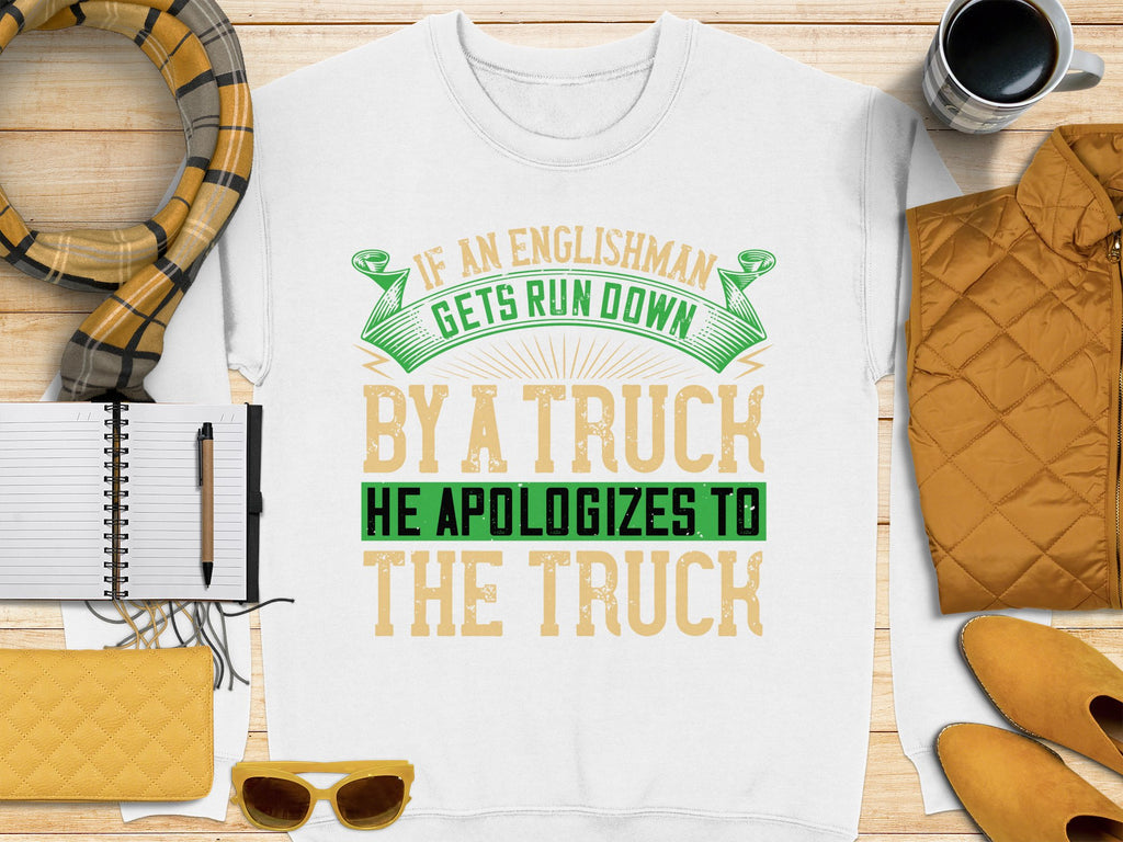 Garment Graphics offers a unisex white t-shirt featuring a bold, humorous design: If an Englishman gets run down by a truck, he apologizes to the truck in green and yellow. Its surrounded by autumn-colored accessories like notebooks and pens.