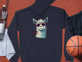 Garment Graphics navy blue classic fit hoodie showcases a llama in funny sunglasses with the phrase No Prob-Llama. Nearby are a water bottle, towel, black shorts, and an orange basketball on a textured surface.