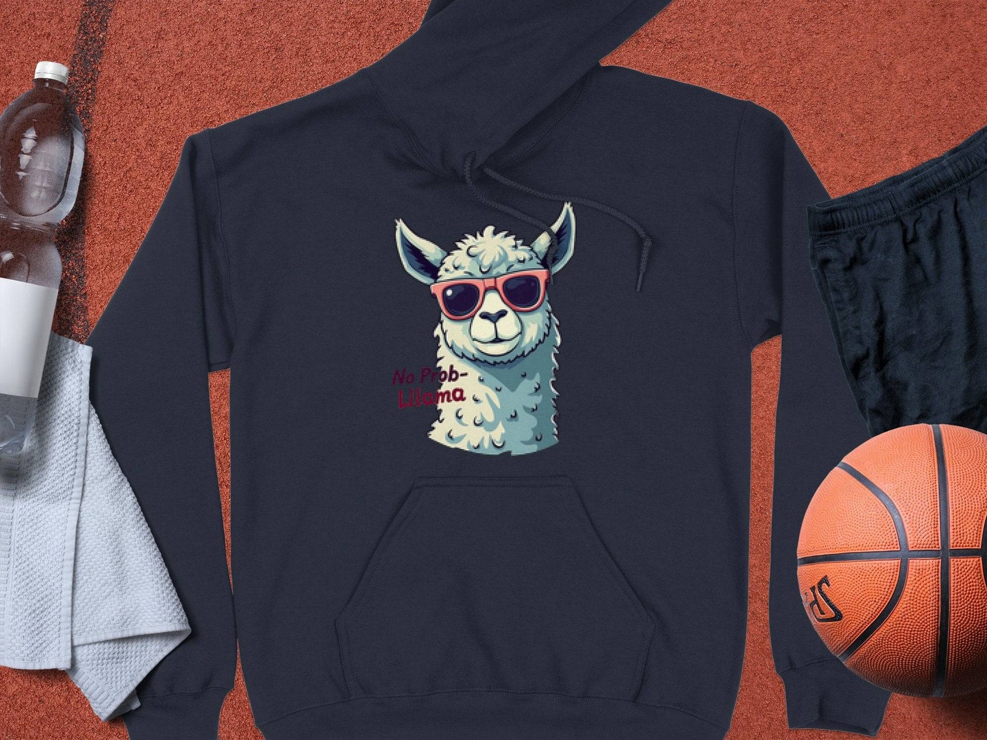 Garment Graphics navy blue classic fit hoodie showcases a llama in funny sunglasses with the phrase No Prob-Llama. Nearby are a water bottle, towel, black shorts, and an orange basketball on a textured surface.