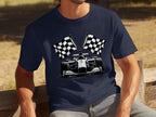 A man relaxes on a wooden bench surrounded by greenery, wearing a navy blue Garment Graphics T-shirt featuring a Formula 1 car with crossed checkered flags, embodying the spirit of motorsport.