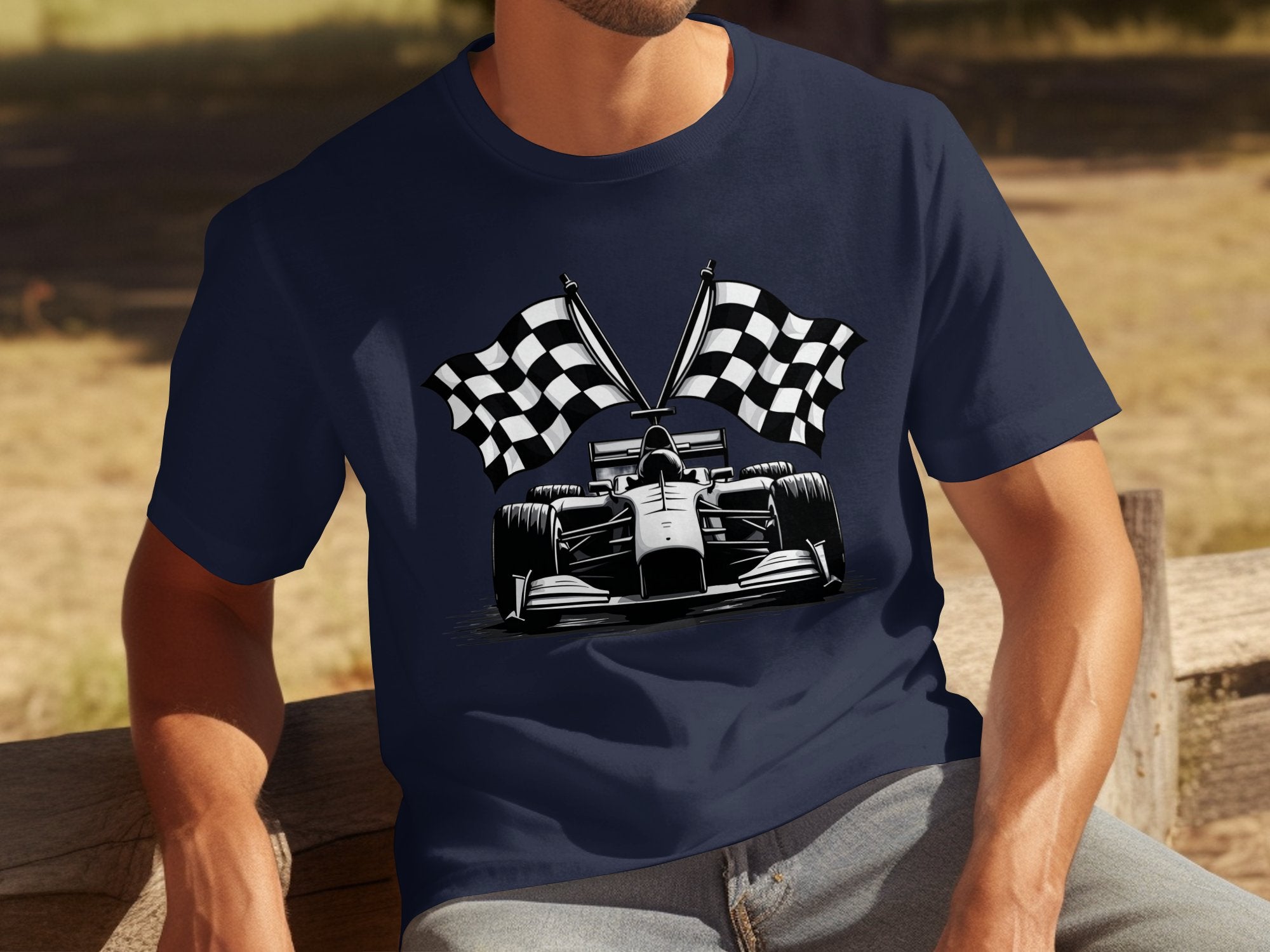 A man relaxes on a wooden bench surrounded by greenery, wearing a navy blue Garment Graphics T-shirt featuring a Formula 1 car with crossed checkered flags, embodying the spirit of motorsport.