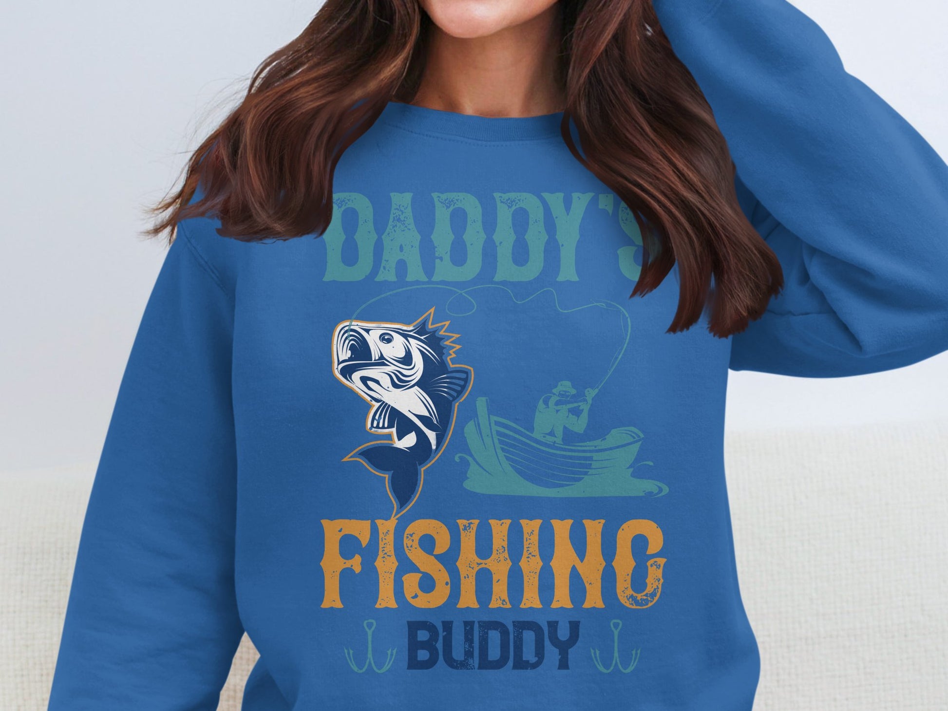 A fishing enthusiast wears Garment Graphics blue sweatshirt emblazoned with Daddys Fishing Buddy and features a fishing boat illustration. Its an ideal choice for those who cherish quality time casting lines and sharing adventures.