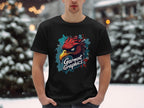 Amidst a snowy scene, someone wears a black Garment Graphics T-shirt in classic fit featuring an eagle design. Their hands are in their pockets while blurred lights twinkle softly behind them.