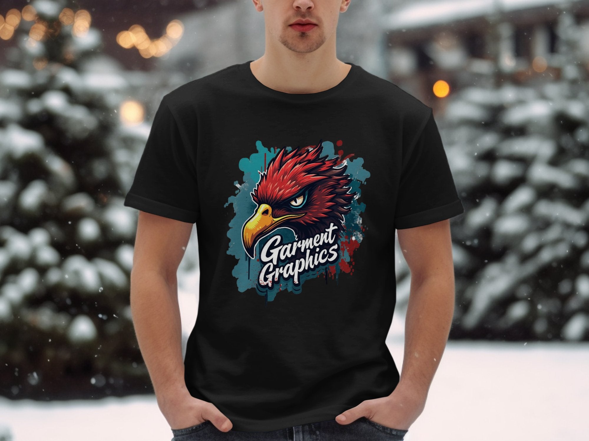 Amidst a snowy scene, someone wears a black Garment Graphics T-shirt in classic fit featuring an eagle design. Their hands are in their pockets while blurred lights twinkle softly behind them.
