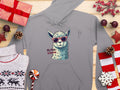 Garment Graphics presents a gray unisex hoodie with a graphic alpaca in red sunglasses and the text No Prob-Llama, elegantly set against a festive wooden background adorned with wrapped gifts, cozy sweater, pine cones, candy, and decorative stars.