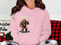 A cool character relaxes on the couch in a pink classic fit hoodie by Garment Graphics. The design shows a cartoon Bigfoot flashing two fingers with the text ADMIT IT. Life Would Be Boring Without Me. Cozy red and black checkered fabric completes the look.