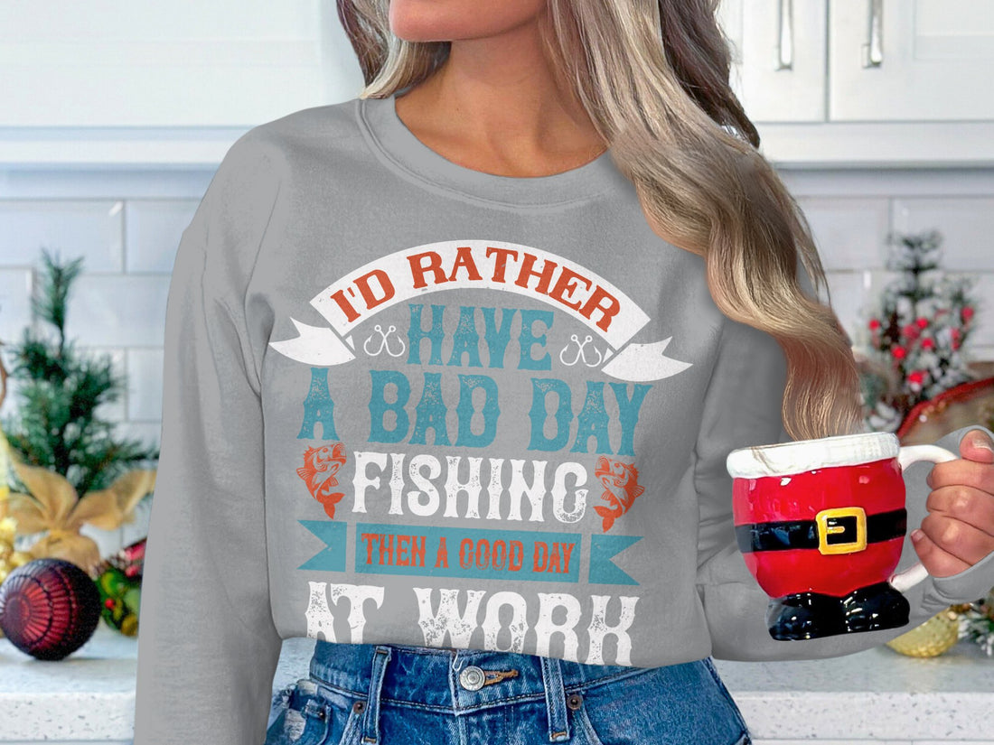 Someone is wearing a Garment Graphics unisex fishing sweatshirt featuring the text Id rather have a bad day fishing than a good day at work in a stylized font, highlighting their preference for angling over office tasks.