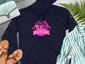 Garment Graphics offers a navy hoodie with a vibrant design of three women and the text Always Party Beach Girl Hoodies. It pairs effortlessly with tan sandals, a striped shirt, watch, purse, and green fern leaves on a gray background for casual style.