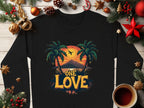 Garment Graphics offers a black sweatshirt featuring One Love in bold yellow and orange with palm trees, a sunset, and a small airplane, encircled by festive decorations and a steaming cup of coffee, capturing the warmth of the One Love Sunset.