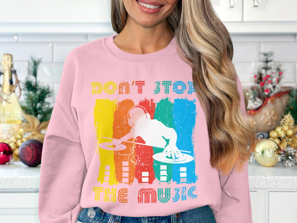 In a festive kitchen adorned with pine cones and ornaments, someone wears a Garment Graphics pink sweatshirt featuring a vibrant DJ design and the inspiring message Dont Stop the Music, perfectly encapsulating the spirit of music lovers.