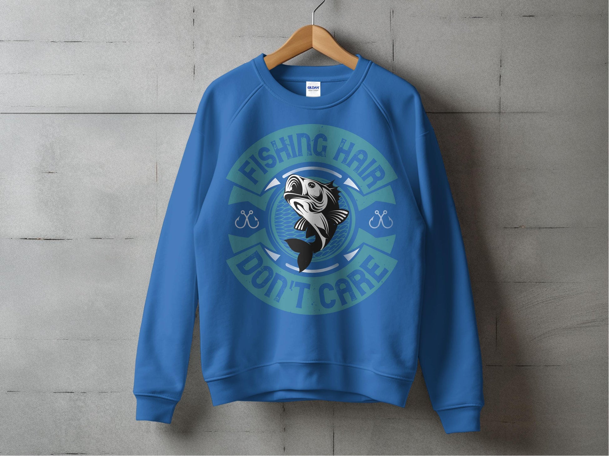 A blue sweatshirt from Garment Graphics hangs on a wooden hanger against a concrete wall. Featuring a stylized fish graphic and the phrase Fishing Hair Dont Care, its ideal for any fishing enthusiast.