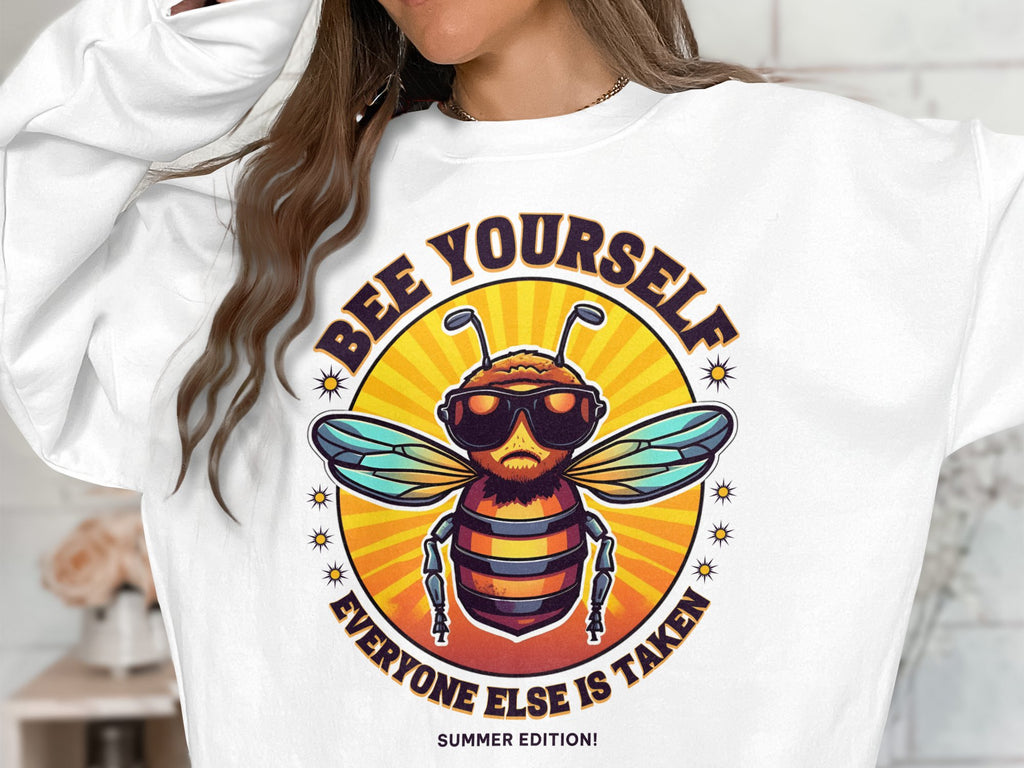 A person is donning a Garment Graphics summer edition unisex sweatshirt, featuring a bearded bee in sunglasses with the text Bee Yourself, Everyone Else is Taken, set against a vivid orange and yellow backdrop.