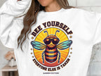 A person is donning a Garment Graphics summer edition unisex sweatshirt, featuring a bearded bee in sunglasses with the text Bee Yourself, Everyone Else is Taken, set against a vivid orange and yellow backdrop.