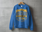 Garment Graphics presents a blue sweatshirt with a humorous message in gold and white: If hes got golf clubs in his truck or a camper in his driveway, I dont hire him. This casual piece is displayed on a wooden hanger against a concrete wall backdrop.