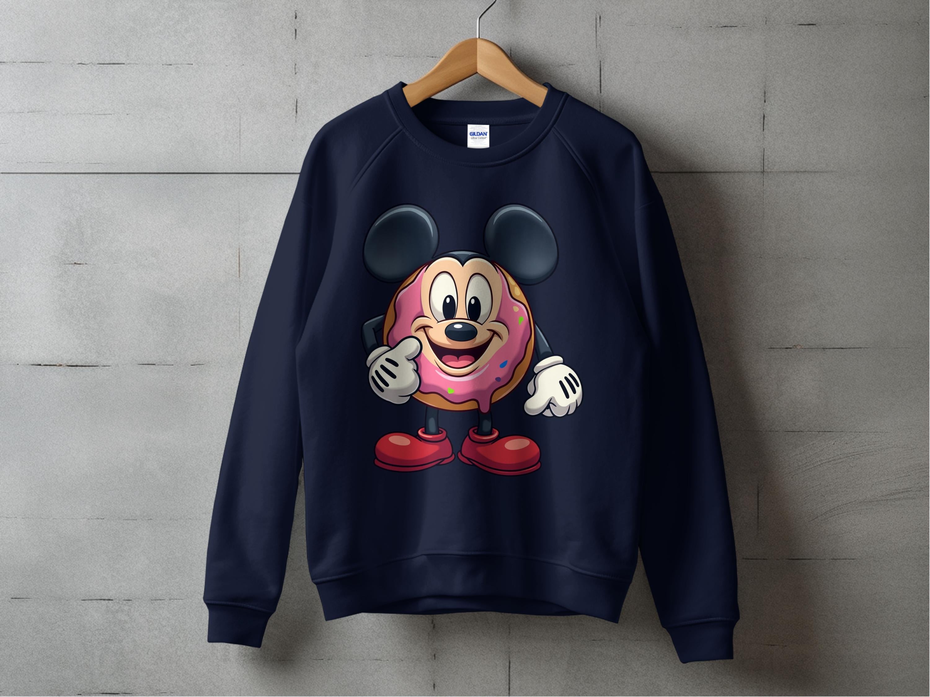 A navy blue Garment Graphics sweatshirt hangs on a wooden hanger with a quirky graphic—a character with big black ears, red shoes, and a cute cartoon sprinkle donut in the center—adding playful charm to any outfit.