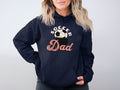 Against a plain background, a person with shoulder-length wavy hair adds casual flair to their look in a navy Soccer Dad hoodie by Garment Graphics, featuring a striking soccer ball graphic print.