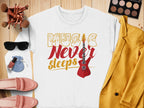Flat lay of a Garment Graphics sweatshirt featuring Music Never Sleeps Guitar with a red guitar graphic. Surrounding it are a mustard jacket, sunglasses, makeup brushes, palette, pink shoes, nail polish, and blue pouch on a wooden surface—a perfect choice for music lovers.