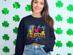 A long-haired person smiles in front of a wall of green shamrocks, wearing Garment Graphics urban-style sweatshirt featuring vibrant graffiti text: I [heart] Graffiti.