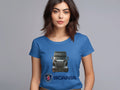 A woman with long brown hair wears a vibrant Garment Graphics T-shirt featuring a Scania truck and logo. Ideal for automotive fans, she stands against a gray background, gazing forward.