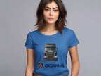 A woman with long brown hair wears a vibrant Garment Graphics T-shirt featuring a Scania truck and logo. Ideal for automotive fans, she stands against a gray background, gazing forward.