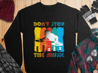 Garment Graphics presents a black sweatshirt for music lovers, featuring a vibrant DJ design with turntables and Dont Stop The Music boldly inscribed above and below. Displayed on a wooden surface, its surrounded by cozy winter clothing items.