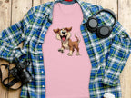 A dog lovers pink T-shirt from Garment Graphics, featuring a cartoon dog print, is spread over a blue and green plaid shirt. Nearby are a camera, headphones, and a take-out cup with lid, all placed on a wooden surface.