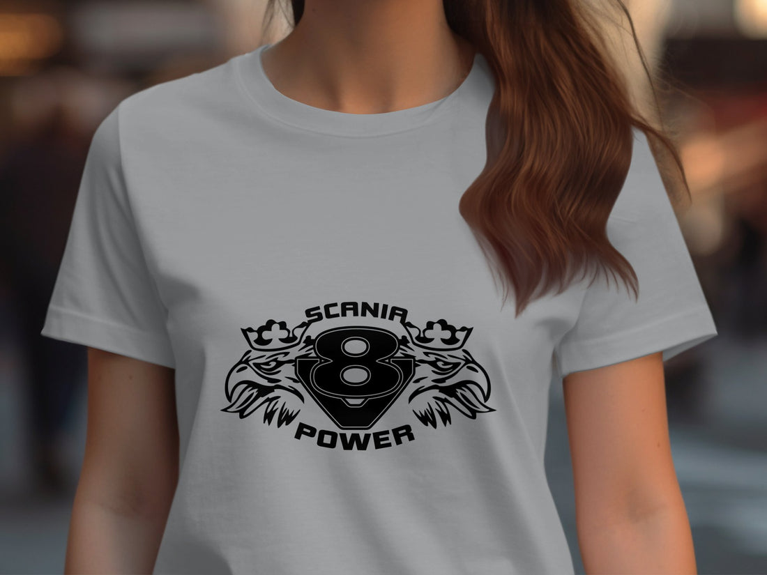 Wearing a light-colored T-shirt from Garment Graphics, the person showcases the SCANIA 8 POWER design, highlighted by stylized lions and eagle heads for an edgy effect. The face is not visible.