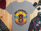 Discover Garment Graphics playful Bee Yourself T-Shirts, Summer Edition! This gray womens tee showcases a bee in sunglasses and headphones, accompanied by a red knit cap, black gloves, plaid shirt, and sunglasses on a wooden surface.