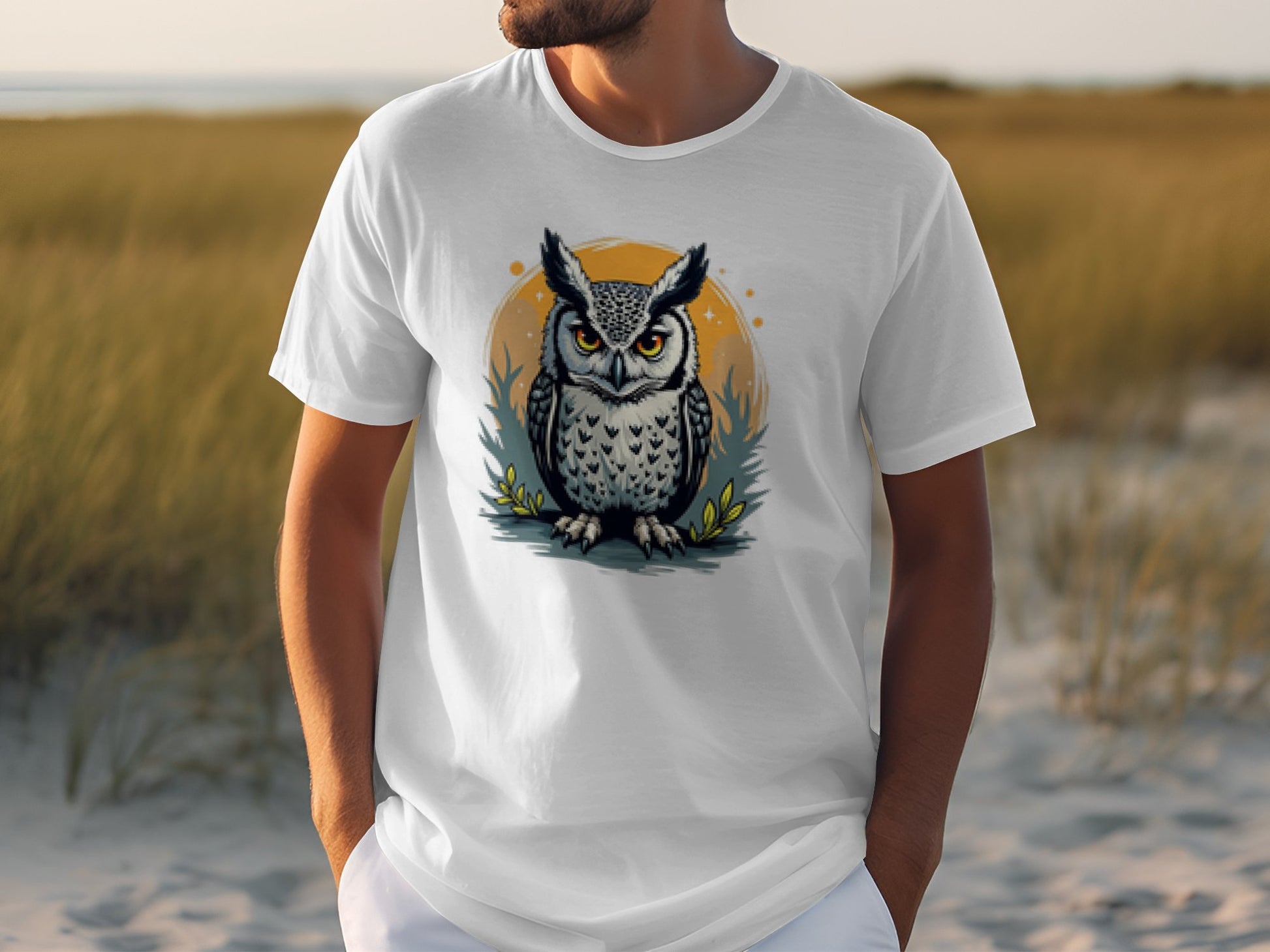 A person dons a Garment Graphics T-shirt showcasing an owl with large eyes inside an orange circle, set against a grassy field under a clear sky, adding charm to the artistic ensemble.