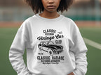 Someone wearing a Garment Graphics Vintage Car Sweatshirt featuring a black-and-white classic vehicle graphic. The text says Classic London City, Vintage Car Club, and Classic Garage Old School Automotive High Style & Cool Life, set against an outdoor sports field backdrop, embodying automotive style.