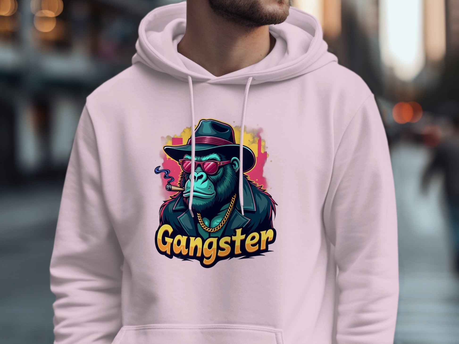 A person is wearing a Garment Graphics hoodie showcasing a gangster ape: a blue gorilla in a hat, sunglasses, and jacket. The word Gangster stands out against a blurred urban street backdrop, perfectly embodying the hipster urban vibe.