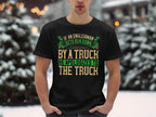 Standing in the snow, a person wears a black Garment Graphics t-shirt with a witty design that humorously captures English politeness: If an Englishman gets run down by a truck, he apologizes to the truck, featuring green and beige text.