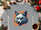 The Garment Graphics gray wolf face sweatshirt showcases a blue and orange illustrated wolf head at its center. Displayed on a wooden surface, it emits unique flair clothing vibes surrounded by Christmas decor, including pine branches, ornaments, and a cozy coffee mug.