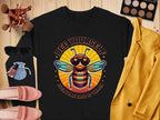 A black sweatshirt from Garment Graphics Summer Edition features a bee with sunglasses and Bee Yourself, Everyone Else is Taken. Perfect for pairing with womens accessories like a yellow jacket, sunglasses, makeup, shoes, and brushes on wood. Available in unisex sizing.