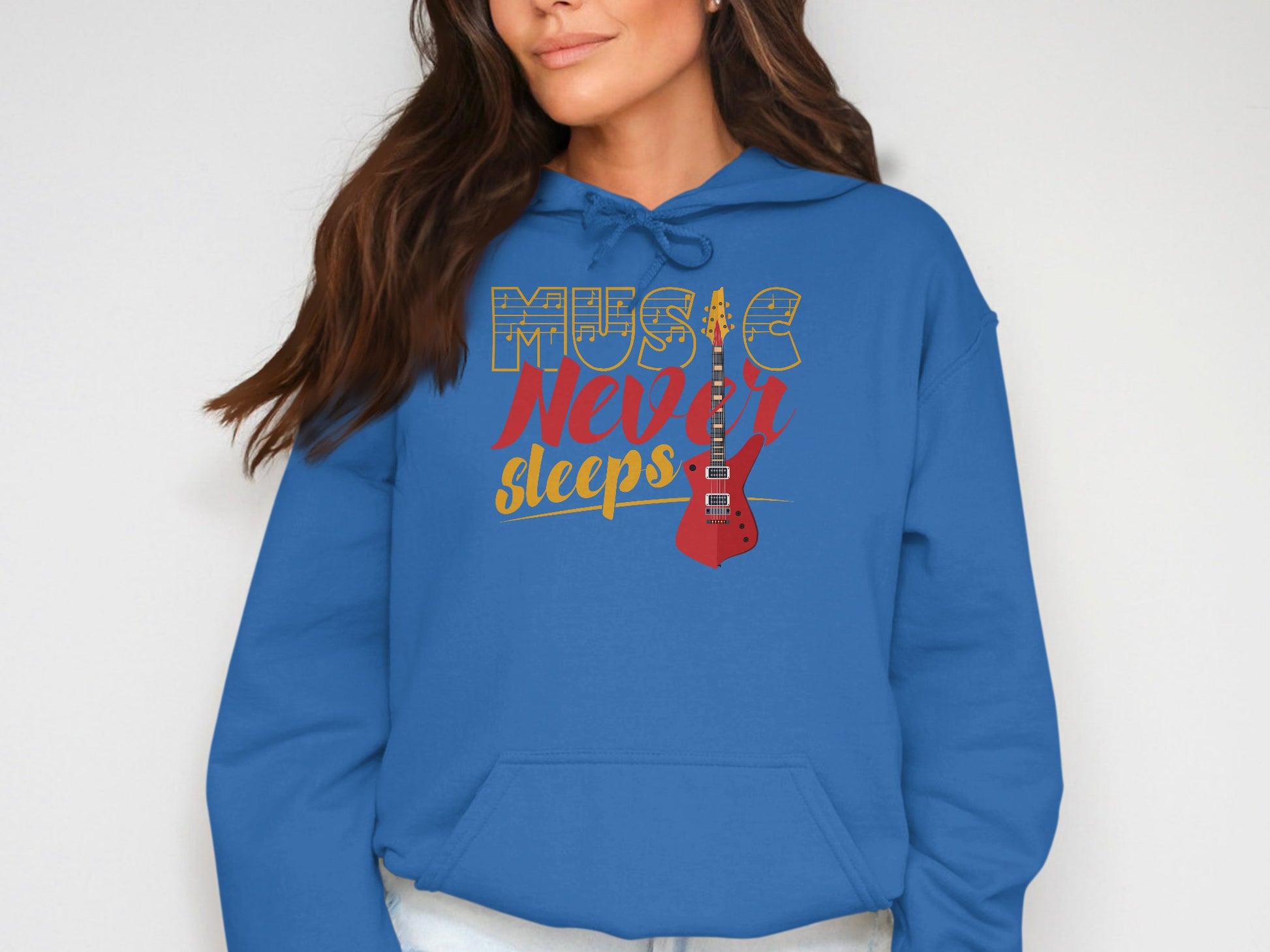 A person wears a Garment Graphics blue hoodie featuring Music Never Sleeps and a red guitar design. This classic-fit music hoodie with drawstrings is worn against a plain background.