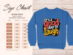 The Garment Graphics Its a Good Day to Laugh sweatshirt has vibrant lettering on a blue background, available in unisex sizing. The detailed Gildan 18000 size chart covers S to 5XL measurements for width and length in inches.