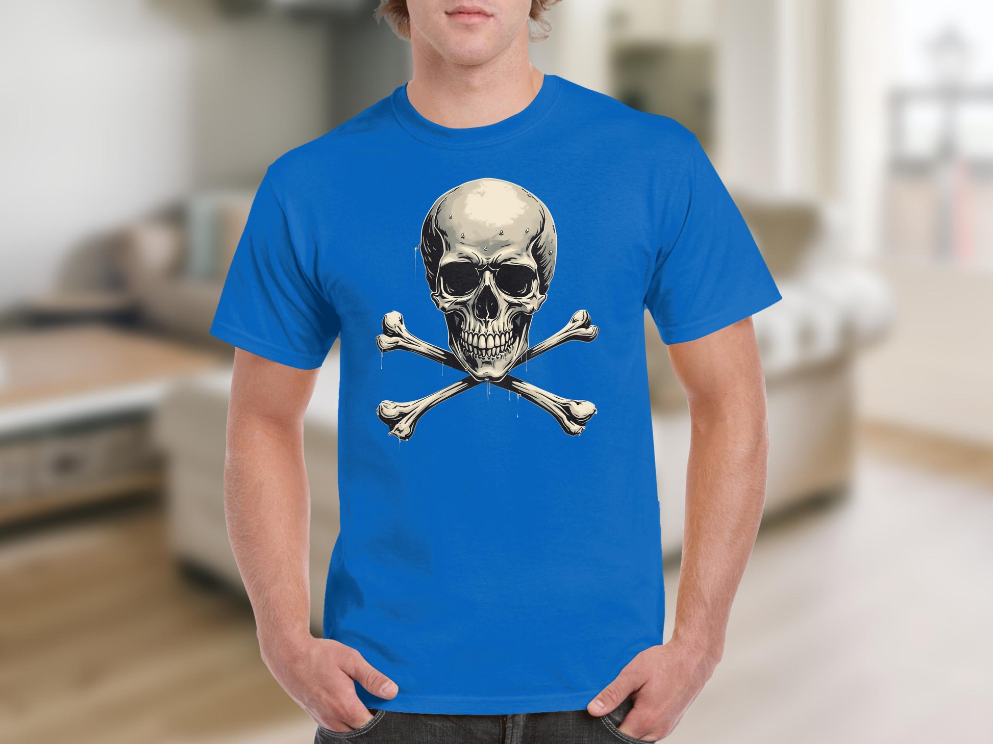 A person stands in a living room, making a bold fashion statement in a Garment Graphics blue graphic t-shirt with a prominent skull and crossbones design. The blurred background reveals cozy furniture and accents.
