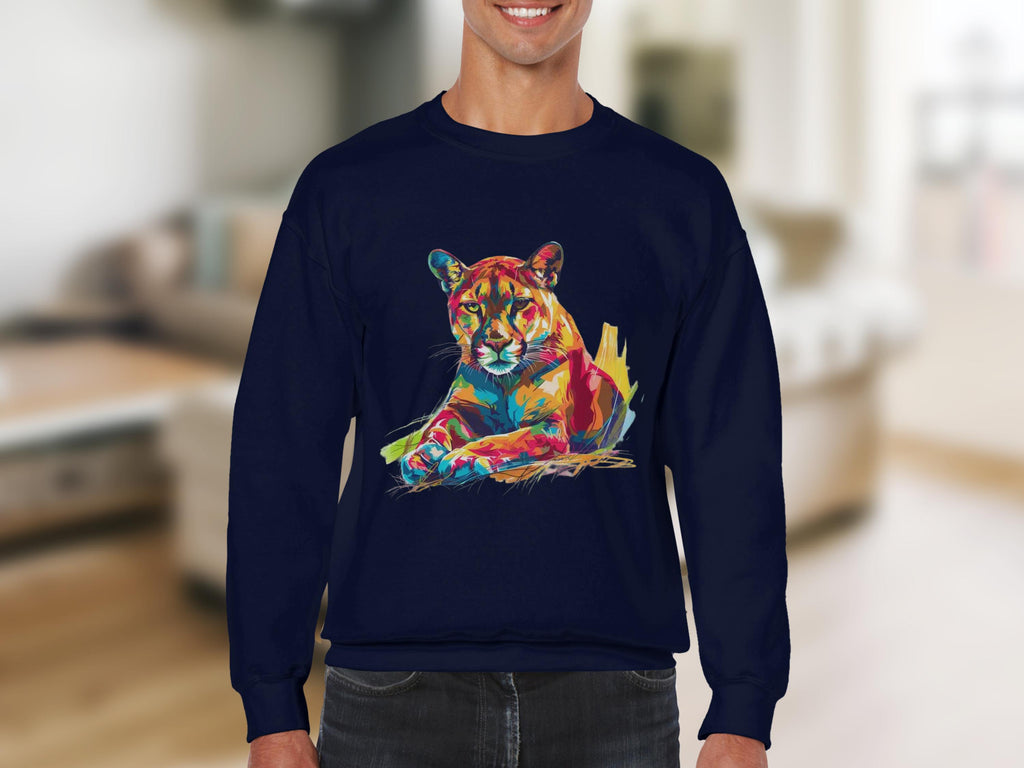 A person wearing Garment Graphics navy blue sweatshirt featuring a vibrant, abstract cougar design lies down in a softly focused indoor setting. This artful fashion piece stands out with unique style and is perfect for unisex sizing enthusiasts.