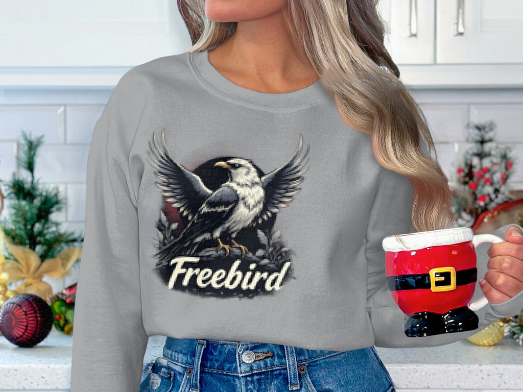 A person with long hair holds a Santa-themed mug, wearing a cozy Garment Graphics sweatshirt with an eagle design. The unisex sizing offers comfort and versatility, as decorative Christmas ornaments twinkle in the background.