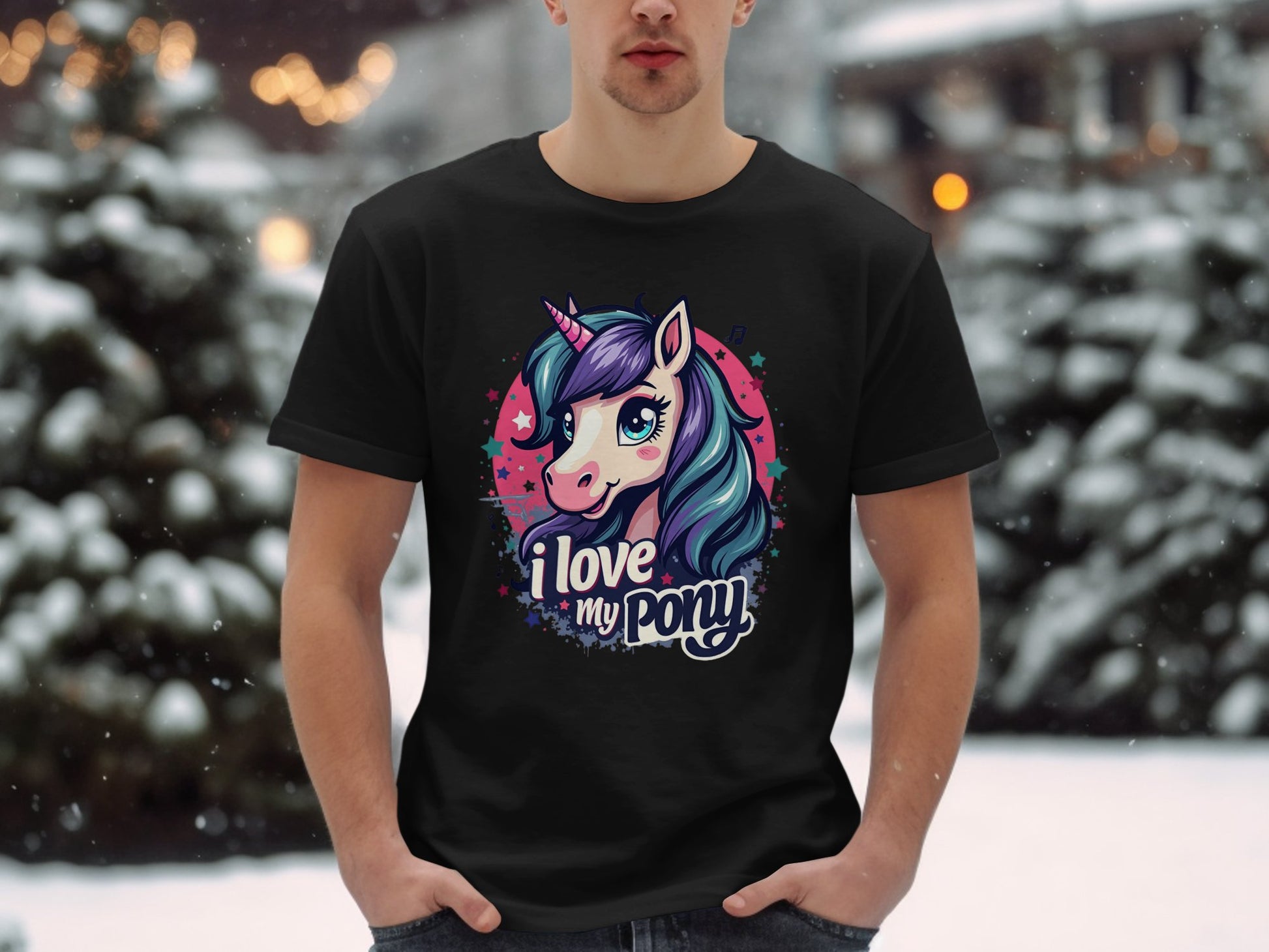 In a snowy outdoor setting, a person wears a black Garment Graphics Unicorn T-shirt with a vibrant pony graphic and the text I love my pony beneath it. Trees and snow form a picturesque backdrop for this unicorn enthusiasts standout piece.