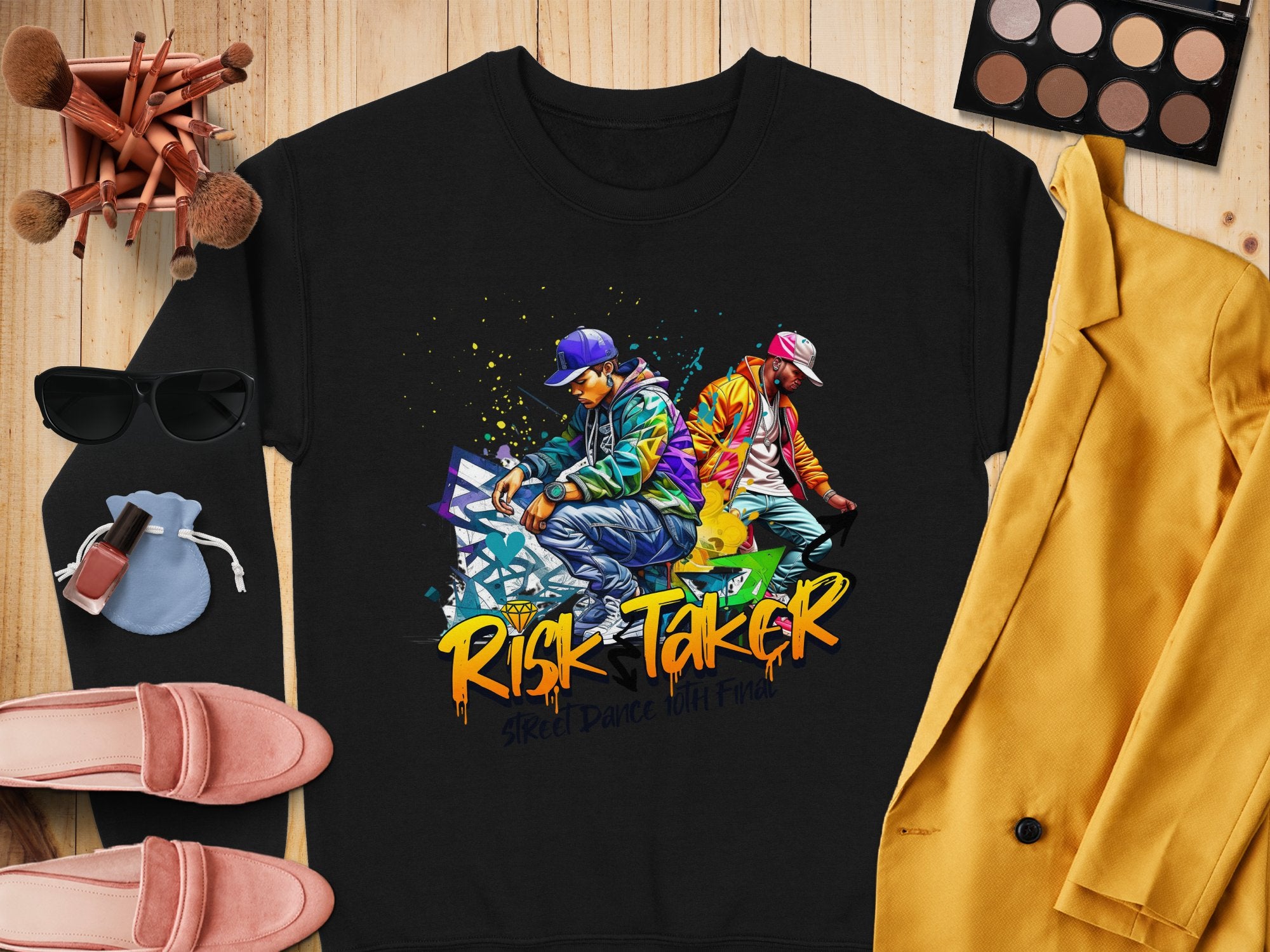 Garment Graphics black sweatshirt features a vibrant graffiti-style image of two posing figures and the text Risk Taker Street Dance. Pair it with a yellow blazer, makeup, sunglasses, moccasins, and a small bag for an ultimate bold look perfect for street dance finals.