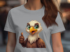A person wears a Garment Graphics light gray eagle T-shirt with a cartoon eagle illustration, featuring green eyes and a yellow beak giving a thumbs-up. The blurred background emphasizes the design, ideal for animal lovers.