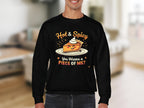 A person wears a black sweatshirt from Garment Graphics Hot and Spicy Sweatshirts collection, featuring a playful pie topped with whipped cream, Hot & Spicy above it, and You Wanna a Piece of Me? below. Its unisex for all to enjoy its charm against a blurred room backdrop.
