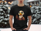 Dressed in a classic fit black Garment Graphics Eagle T-shirt showcasing a cartoon eagle giving a thumbs-up, the individual stands against a snowy backdrop with blurred trees and twinkling lights, enhancing the fun, casual vibe.