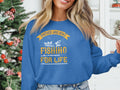 A person in a blue Garment Graphics sweatshirt, ideal for fishing enthusiasts, stands in a Christmas-decorated room. The shirt displays Father and Son Fishing Partners for Life with a boat and fishing rod image.